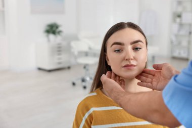 Randevu sırasında klinikte kadının boğazını muayene eden doktor.
