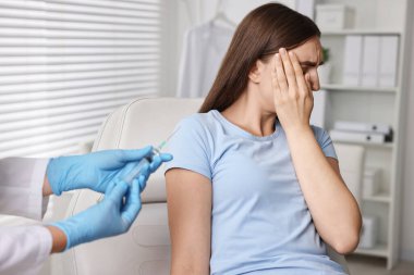 Dental phobia. Dentist with syringe near scared woman in clinic, closeup clipart