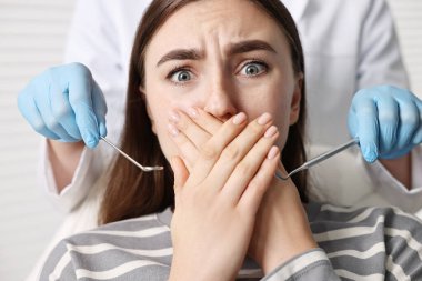 Diş fobisi. Klinikte korkmuş bir kadınla çalışan dişçi, yakın plan.