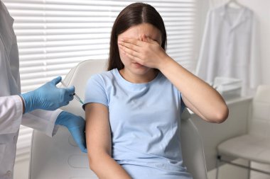Diş fobisi. Şırıngalı dişçi klinikte korkmuş bir kadının yanında, yakın plan.