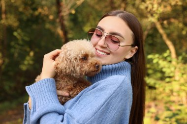 Sonbahar parkında sevimli köpeğiyle gülümseyen kadın.