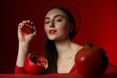 Kırmızı arka planda olgun narı olan kadın.