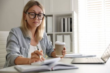 Bütçe planlaması. Kapalı mekanda hesap makinesi kullanan kağıt bardakta kahve içen kadın.