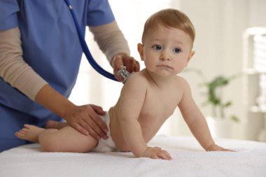Pediyatrist, klinikte steteskoplu küçük bir çocuğu muayene ediyor. Bebeğin sağlığını kontrol ediyorum.