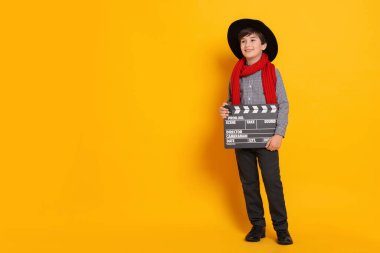 Turuncu arka planda film yönetmeni gibi davranan alkışlı çocuk, mesaj için yer var. Geleceğin mesleğini hayal etmek