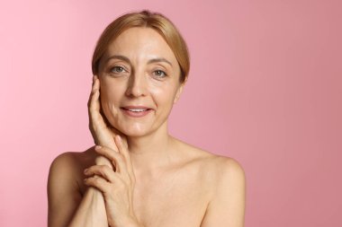Pembe arka planda sağlıklı ciltli gülümseyen kadın portresi. Metin için boşluk
