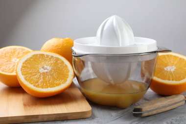 Plastik sıkacağı, portakal ve bıçak gri masada, yakın plan.
