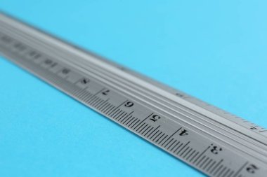 Açık mavi arka planda bir metal cetvel, yakın plan
