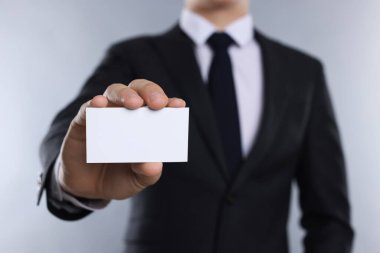 Gri arka planda boş bir kartvizit tutan adam, yakın plan. Tasarım için model