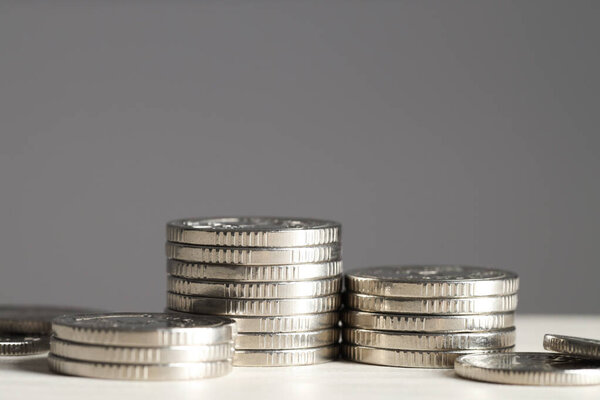 Stacked coins on white wooden table against grey background, closeup. Salary concept