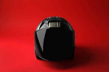 Kırmızı arka planda güneşliği olan modern motosiklet kaskı