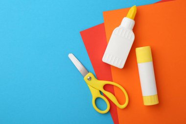 Yapıştırıcı, renkli kağıt ve makas açık mavi arka planda, düz. Metin için boşluk