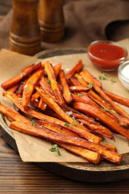 Ahşap masada soslu ve baharatlı leziz patates kızartması.