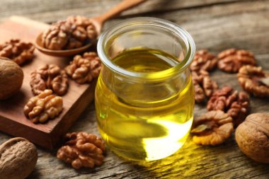 Kavanozda ceviz yağı ve ahşap masada malzemeler, yakın plan.