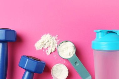 Protein tozu, titretici ve halterler pembe arka planda, düz yerde. Metin için boşluk