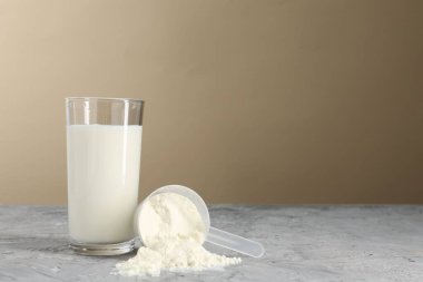 Lezzetli protein karışımı bardakta ve toz tozlu gri desenli masa üzerinde bej arka plan, metin için boşluk