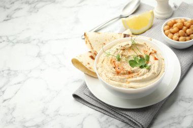 Kırmızı biberli lezzetli humus, beyaz mermer masada pide ve nohut, yazı için yer