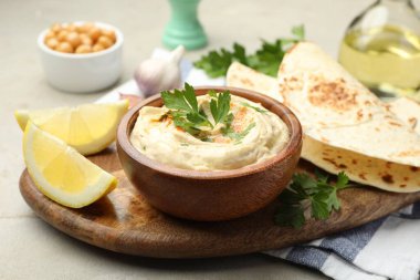 Maydanozlu lezzetli humus, paprika, pide ve limon gri masada, yakın plan.