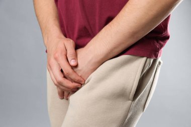 Cinsel yolla bulaşan hastalıklar. Gri arka planda semptomlardan muzdarip bir adam, yakın plan