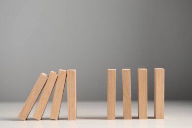 Domino etkisi. Tahta bloklar beyaz masaya düşüyor.