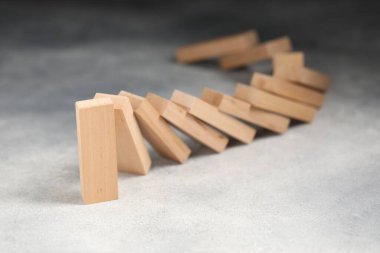 Domino etkisi. Tahta bloklar gri masaya düşüyor, yakın plan.
