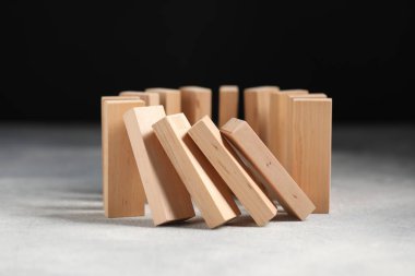 Domino etkisi. Tahta bloklar gri masaya düşüyor, yakın plan.