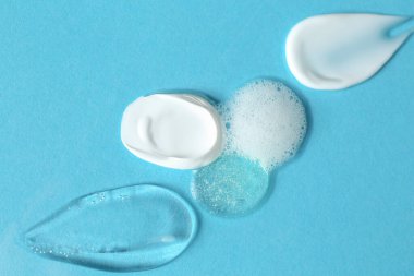 Açık mavi arka planda farklı kozmetik ürünlerinin kokusu, üst görünüm