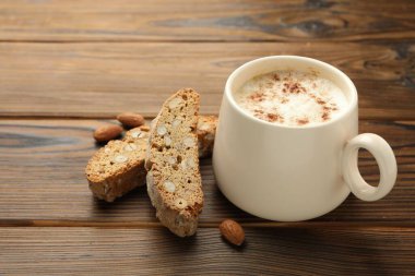 Geleneksel İtalyan badem bisküvileri (Cantucci), fındık ve bir fincan kahve ahşap masada, yakın plan.