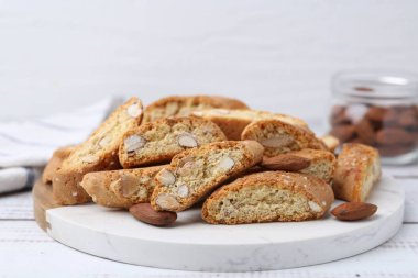 Lezzetli bademli bisküviler (Cantuccini) ve beyaz ahşap masada fındıklar, yakın plan.