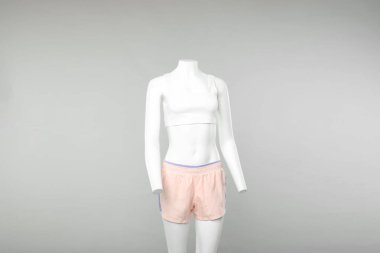 Hafif arka planda şık spor kıyafetleri olan kadın mankeni.