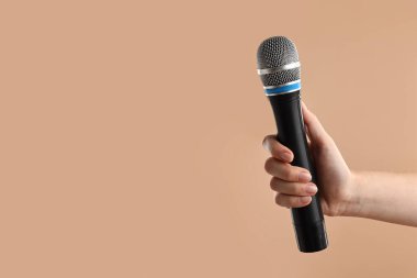Bej arka planda mikrofonu olan bir kadın, yakın plan. Metin için boşluk