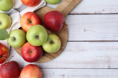 Beyaz ahşap masa üzerinde farklı olgun elmalar, düz uzanmış. Metin için boşluk