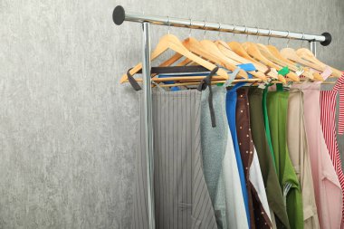 Açık gri duvarın yanında giysi rafında bir sürü şefin önlüğü var.