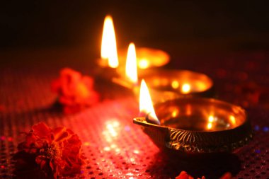 Diwali kutlaması. Diya lambaları ve koyu arkaplanda güzel çiçekler, yakın plan