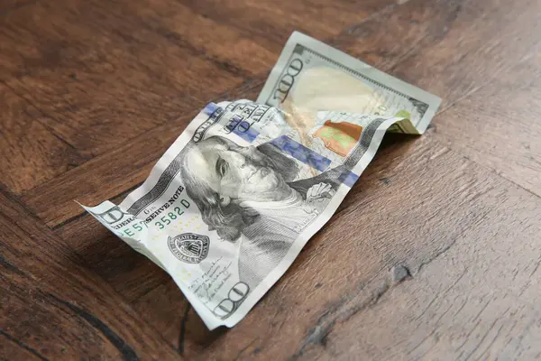 Tahta masanın üzerine buruşmuş bir dolar banknot, yakın plan.