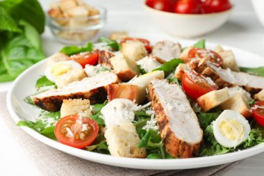 Tasty Caesar salad with chicken and tomatoes on white wooden table, closeup clipart