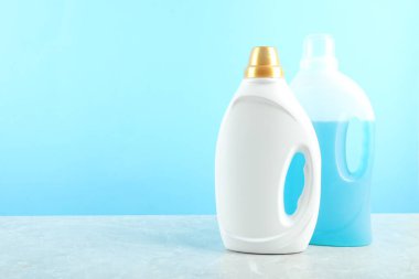 Gri mermer masadaki şişelerde çamaşır deterjanı açık mavi arka planda, metin için boşluk