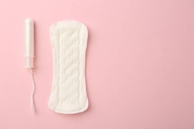 Açık pembe arka planda regl pedi ve tampon, üst manzara. Metin için boşluk