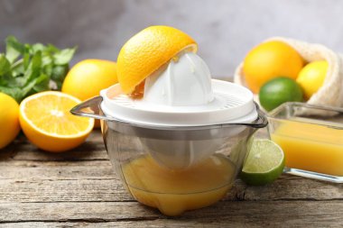 Plastik sıkacağı ve taze portakallar ahşap masada, yakın plan.