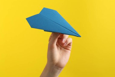 Sarı arka planda mavi kağıt uçaklı kadın, yakın plan.