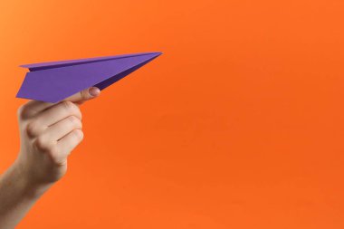 Turuncu arka planda mor kağıt uçaklı kadın, yakın plan. Metin için boşluk
