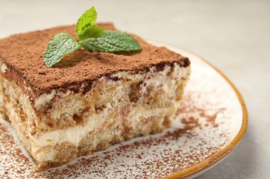 Lezzetli bir tiramisu. Bej masa üzerinde taze nane, yakın plan.