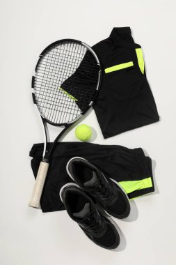 Beyaz arka planda tenis raketi, top ve spor giyim, düz yatış