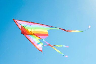 Mavi gökyüzünde uçan renkli bir uçurtma