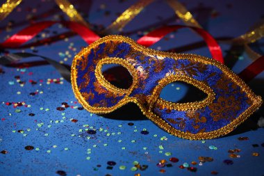 Güzel bir karnaval maskesi, kurdeleler ve mavi arka planda konfeti, yakın plan.
