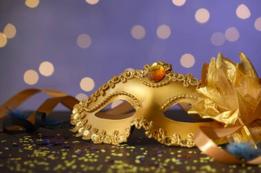 Renkli arka planda güzel bir karnaval maskesi, kurdeleler ve konfeti, bulanık ışıklar, yakın plan