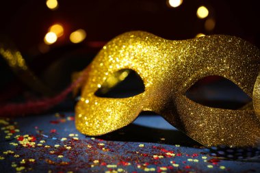 Güzel bir karnaval maskesi ve koyu arkaplanda bulanık ışıkları olan konfeti, yakın plan.