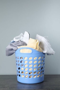 Çamaşır dolu plastik sepet gri arka planda.