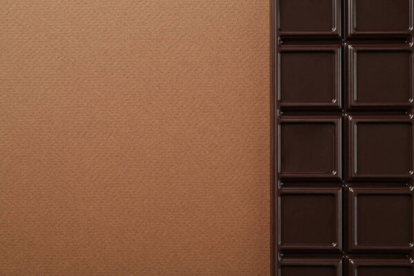 Tasty chocolate bar on brown background, top view. Space for text