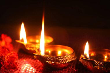 Diwali kutlaması. Diya lambaları ve koyu arkaplanda güzel çiçekler, yakın plan